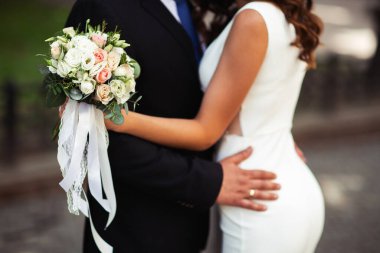 Güzel bir düğün çifti el ele tutuşuyor ve çiçekler açıyor. Çok heyecanlı bir an. Klasik gelinlik ve erkek kostümü. Düğün salonu reklamı için. Düğün afişi. Yatay