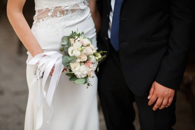 Güzel bir düğün çifti el ele tutuşuyor ve çiçekler açıyor. Çok heyecanlı bir an. Klasik gelinlik ve erkek kostümü. Düğün salonu reklamı için. Düğün afişi. Yatay