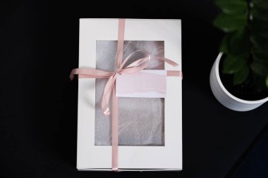 Koyu renkli bir zıtlık zeminine sahip beyaz hediye kutusu, desenli pembe fiyonk ve kartpostalla süslenmiş romantik bir atmosfer yaratıyor. Genelde doğum günü ve yıldönümü hediyeleri için kullanılır. Tatil dekorasyonları