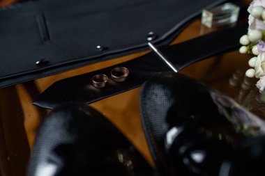 Damat sabah toplanıyor. Siyah erkek klasik deri ayakkabılar, kravat ve yelek. Siyah kuşak. Düğün detayları. Eau de Tuvalet, parfüm, deri kol saati. Evlilik yüzükleri..