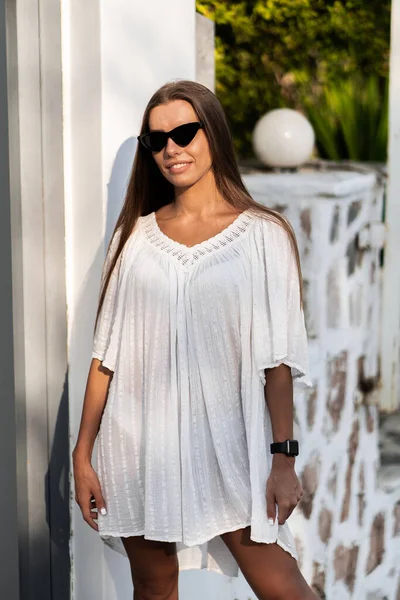 Joven mujer hermosa en vestido blanco y gafas de sol se da la vuelta en la carretera con las palmas. El concepto de alegría, facilidad y libertad durante las vacaciones. La chica está disfrutando del resto. Moda — Foto de Stock