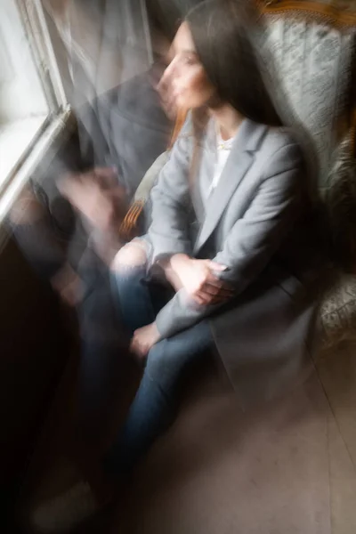 Jovem mulher refrigeração em casa em cadeira confortável. Menina relaxante e esperando por alguém. Jovem mulher em casa sentado na cadeira moderna perto da janela relaxante na sala de estar e olhando para a janela . — Fotografia de Stock