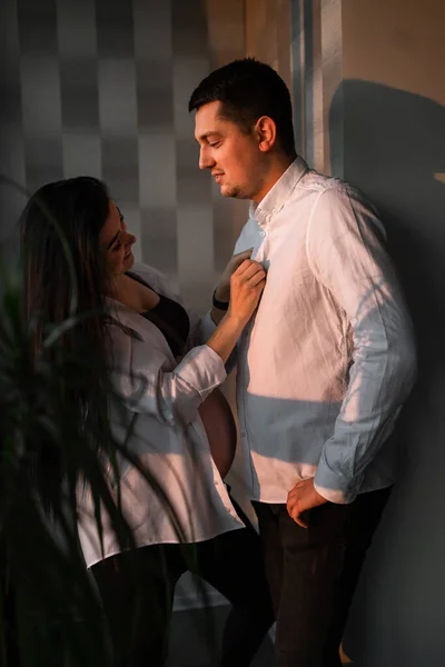 Romantyczna para spodziewająca się dziecka, trzymająca się za ręce i dotykająca czoła, stojąca razem przy oknie w domu, wolna przestrzeń. Ciąża, macierzyństwo, przygotowanie i koncepcja oczekiwań. C — Zdjęcie stockowe
