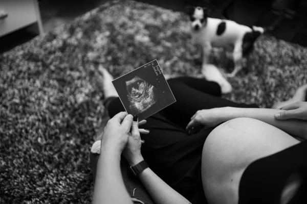 Gehakt beeld van een mooie zwangere vrouw en haar knappe man met een echo. Zwangerschap, moederschap, voorbereiding en verwachting — Stockfoto