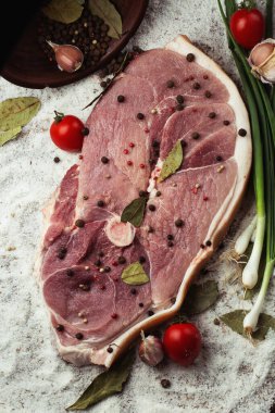 Ahşap arka planda çiğ domuz budu dilimleri. Sebzelerle izole edilmiş çiğ domuz eti. Et dükkanı ve çiftlik reklamı. Çeşitli et çeşitleri ve pişirmeye hazır konsept. Üst görünüm.