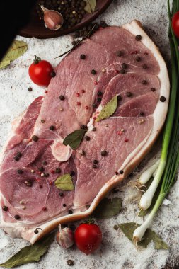 Ahşap arka planda çiğ domuz budu dilimleri. Sebzelerle izole edilmiş çiğ domuz eti. Et dükkanı ve çiftlik reklamı. Çeşitli et çeşitleri ve pişirmeye hazır konsept. Üst görünüm.