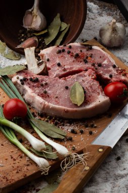 Otlu çiğ et, tahta arka planda bıçak ve baharatlar. İki çiğ domuz eti. Et pişirmek için gerekli malzemeler. Et dükkanı ve çiftlik reklamı. Çeşitli et çeşitleri ve pişirmeye hazır konsept..
