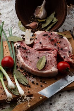 Otlu çiğ et, tahta arka planda bıçak ve baharatlar. İki çiğ domuz eti. Et pişirmek için gerekli malzemeler. Et dükkanı ve çiftlik reklamı. Çeşitli et çeşitleri ve pişirmeye hazır konsept..