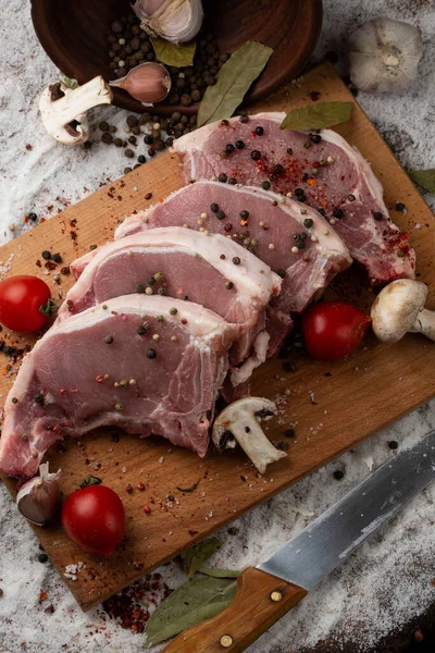 Meat, pork, steaks pork loin on a wooden background. Raw pork marinated meat isolated with vegetables. Advertising for meat shop and farm. Various kinds of meat and ready to cook concept. Top view.