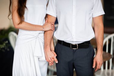 Güzel bir düğün çifti el ele tutuşuyor ve çiçekler açıyor. Çok heyecanlı bir an. Klasik gelinlik ve erkek kostümü. Düğün salonu reklamı için. Düğün afişi. Yatay