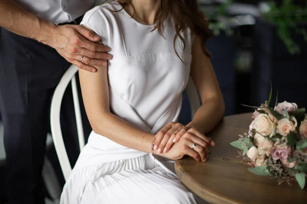 Düğün dergileri, web siteleri, bohem, moda, çiçekçi için mükemmel bir görüntü. Boşluğu kopyala. Çift oturuyor, sarılıyor ve düğün buketinin yanında yüzüklerini gösteriyor..