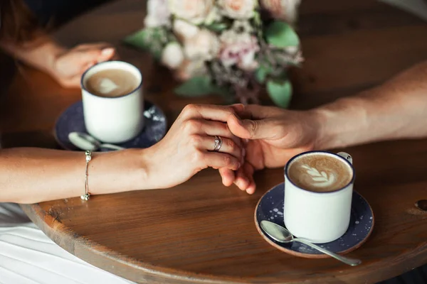 Perfect image with copy space for wedding magazines and websites, bohemian, fashion, florist. Copy the space. Couple sitting, hugging and showing rings near wedding bouquet.