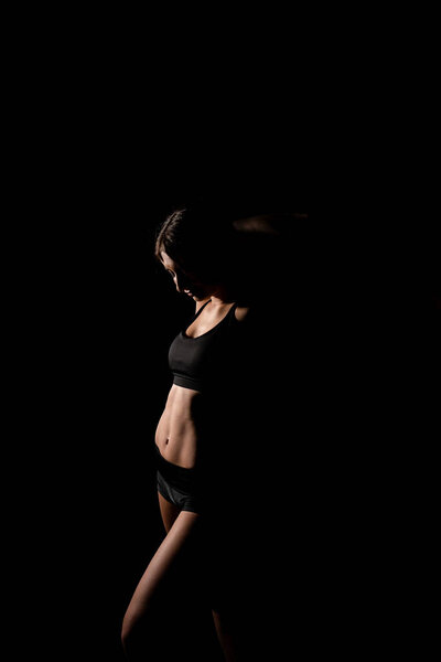 Close up girl shows sports stomach. Healthy fitness and eating lifestyle concept. Fitness sporty woman showing her well trained body, isolated over black background.