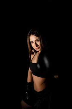 Karanlık ringde kadın boksör eğitimi. Ağır çekim. Siluet. Boks konsepti. Dövüşçü kadın yumruğunu sık. Seyirci video boks maçı. Spor salonunda eldivenlerle gülümseyen kız boksu..