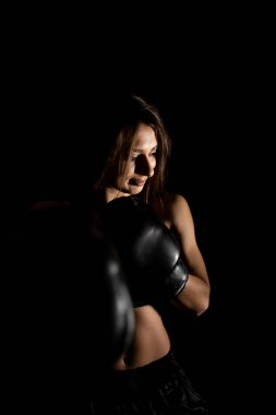 Karanlık ringde kadın boksör eğitimi. Ağır çekim. Siluet. Boks konsepti. Dövüşçü kadın yumruğunu sık. Seyirci video boks maçı. Spor salonunda eldivenlerle gülümseyen kız boksu..