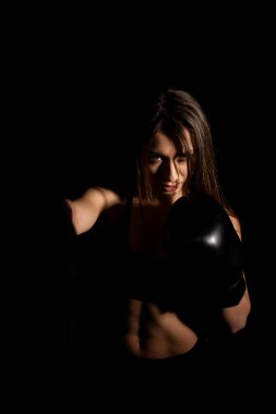 Karanlık ringde kadın boksör eğitimi. Ağır çekim. Siluet. Boks konsepti. Dövüşçü kadın yumruğunu sık. Seyirci video boks maçı. Spor salonunda eldivenlerle gülümseyen kız boksu..