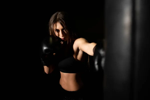 Female boxer training in the dark ring. Slow motion. Silhouette. Boxing concept. Fighter woman fist close up. Spectator video boxing. Smiling girl boxing at fitness gym in gloves.