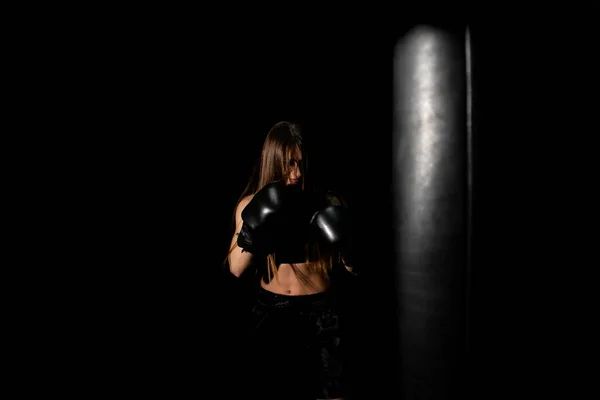 女拳击手在黑暗圈子里训练 慢动作剪影 拳击的概念 女战士的拳头紧紧地握紧了 观众视频拳击 带着手套在健身馆打女子拳击 — 图库照片