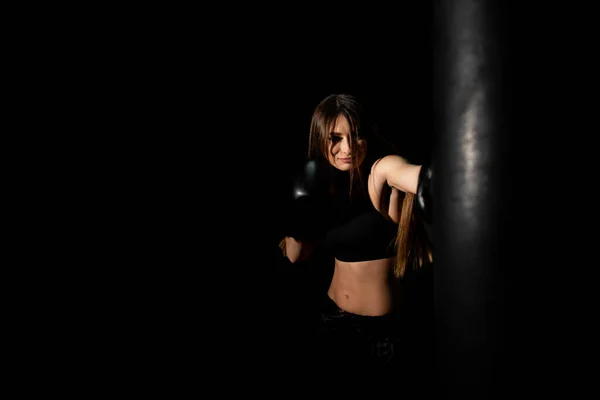 Female boxer training in the dark ring. Slow motion. Silhouette. Boxing concept. Fighter woman fist close up. Spectator video boxing. Smiling girl boxing at fitness gym in gloves.