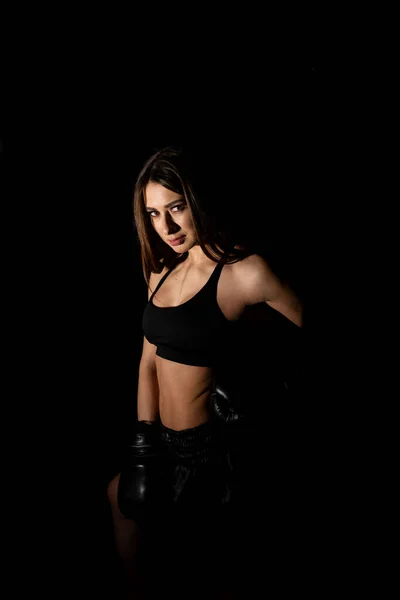 Female boxer training in the dark ring. Slow motion. Silhouette. Boxing concept. Fighter woman fist close up. Spectator video boxing. Smiling girl boxing at fitness gym in gloves.