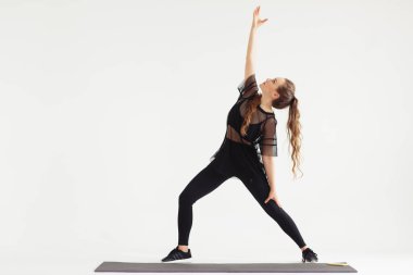 Yoga yapan, Utthita Trikonasana egzersizi yapan, uzun üçgen pozu veren, spor giyinen, siyah pantolonlu, üstsüz, kapalı alanda uzun boylu bir kadın.,