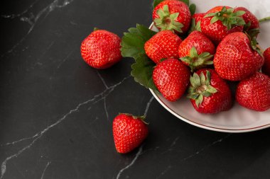 Siyah mermer masadaki kasede taze çilekler. Taze çilekler. Meyve suyu çileği. Meyve çiftliğindeki çilek tarlası. Taze olgun organik çilek beyaz sepetin içinde çilek yatağının yanında kendi böğürtlen tarlanızı seçin..