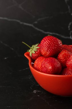 Siyah mermer masadaki kasede taze çilekler. Taze çilekler. Meyve suyu çileği. Meyve çiftliğindeki çilek tarlası. Taze olgun organik çilek beyaz sepetin içinde çilek yatağının yanında kendi böğürtlen tarlanızı seçin..