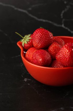 Siyah mermer masadaki kasede taze çilekler. Taze çilekler. Meyve suyu çileği. Meyve çiftliğindeki çilek tarlası. Taze olgun organik çilek beyaz sepetin içinde çilek yatağının yanında kendi böğürtlen tarlanızı seçin..