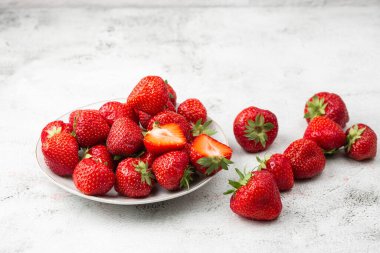 Siyah mermer masadaki kasede taze çilekler. Taze çilekler. Meyve suyu çileği. Meyve çiftliğindeki çilek tarlası. Taze olgun organik çilek beyaz sepetin içinde çilek yatağının yanında kendi böğürtlen tarlanızı seçin..