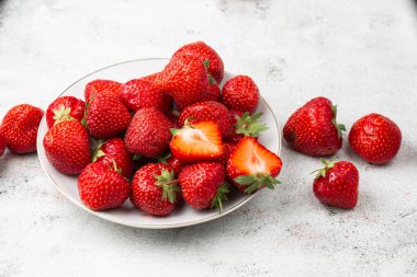 Siyah mermer masadaki kasede taze çilekler. Taze çilekler. Meyve suyu çileği. Meyve çiftliğindeki çilek tarlası. Taze olgun organik çilek beyaz sepetin içinde çilek yatağının yanında kendi böğürtlen tarlanızı seçin..