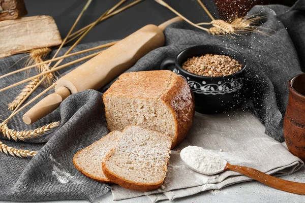 Close-up of homemade bread. Peasant square bread and wheat spikelets with space for text. Homemade baking. Sliced gray bread with flour on wooden chopping board
