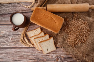 Ev yapımı ekmeğin yakın çekimi. Köylü karesi ekmek ve yazı için yeri olan buğday dikenleri. Ev yapımı pişirme. Unlu beyaz ekmek ve tahtadan kesilmiş süt.