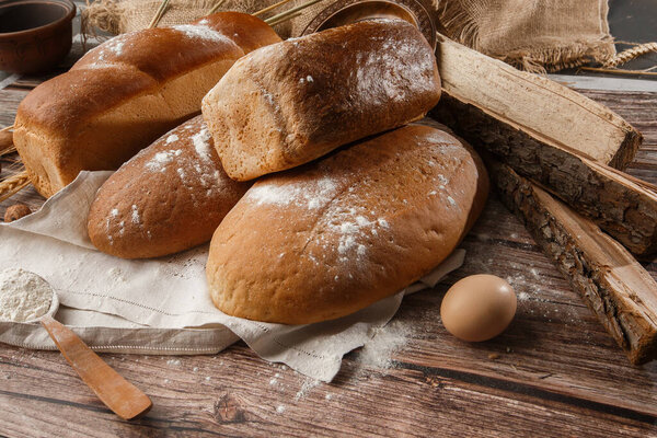 Different kinds of fresh bread as background, top view. Bakery - gold rustic crusty loaves of bread and buns on black chalkboard background. Still life captured from above.