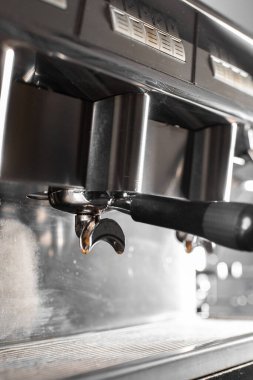 Profesyonel makineden fincana kahve dökülüyor. Barista espresso yapıyor, filtre tutacağı kullanıyor. Taze kahve akıyor. Sabahları kavrulmuş sade kahve içmek..