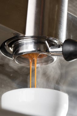 Profesyonel makineden fincana kahve dökülüyor. Barista espresso yapıyor, filtre tutacağı kullanıyor. Taze kahve akıyor. Sabahları kavrulmuş sade kahve içmek..