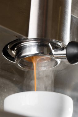 Profesyonel makineden fincana kahve dökülüyor. Barista espresso yapıyor, filtre tutacağı kullanıyor. Taze kahve akıyor. Sabahları kavrulmuş sade kahve içmek..