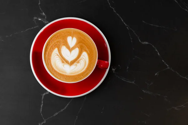 Tazza rossa di caffè latte caldo con bella schiuma di latte latte texture art isolato su sfondo di marmo scuro. Vista aerea, copiare spazio. Pubblicità per il menu del caffè. Menù caffetteria. — Foto Stock