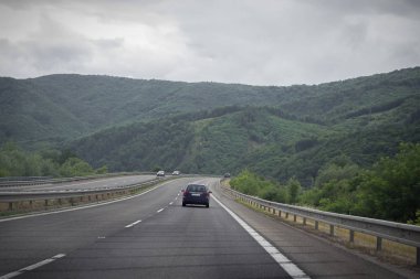 Asfalt yol ve bulutlu gökyüzü ile dağlarda araba