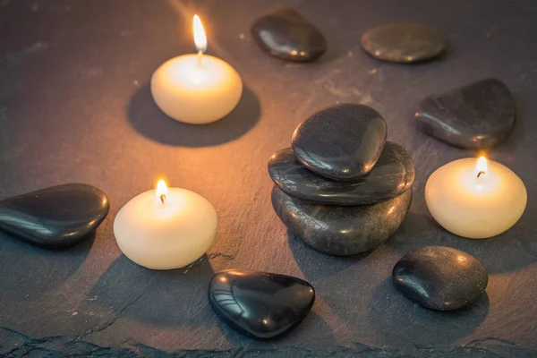 Zwarte stenen en brandende kaarsen op donkere achtergrond — Stockfoto