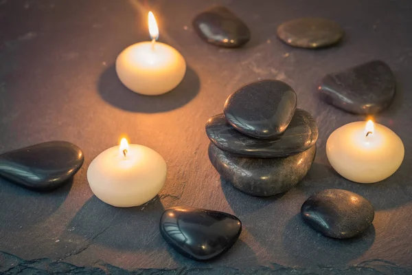 Piedras negras y velas encendidas sobre fondo oscuro —  Fotos de Stock