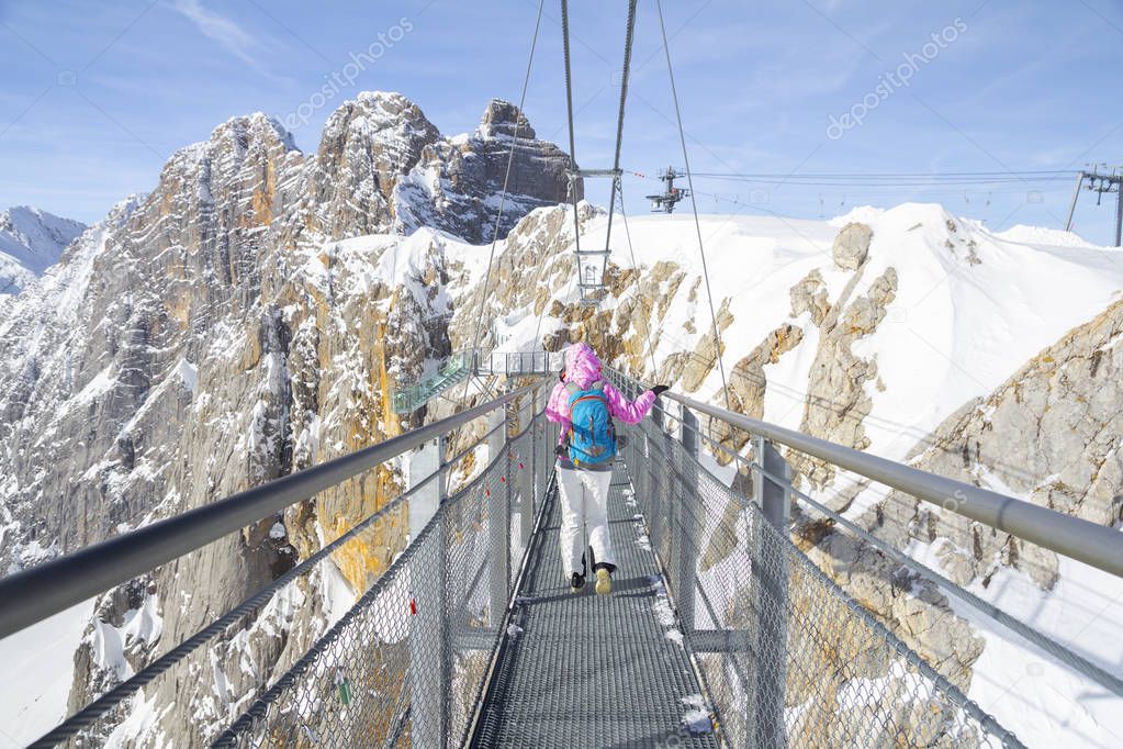 woman walking across rope bridge on Dachstein mountain