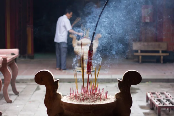 Hoi An, Vietnam - Junio 2017: hombre quemando incienso en templo chino, Hoi An, Vietnam . — Foto de Stock