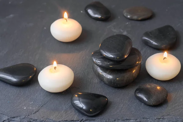 Pierres noires et bougies allumées sur fond sombre — Photo