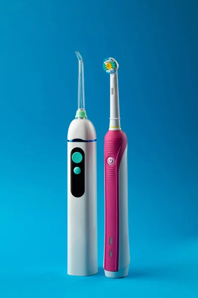 Cepillo de dientes e irrigador con un cartucho de hilo dental sobre fondo pastel azul, vista vertical Fotos De Stock