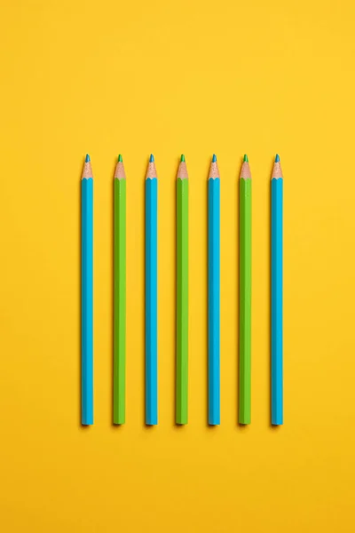 Yeşil ve mavi kalem kopya alanı ile sarı pastel arka plan üzerinde paralel