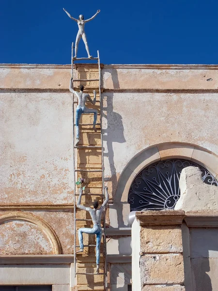 De decoratie van het niet-geïdentificeerde gebouw, vertegenwoordigt de klimmen mannen op de stap en een vrouw stond op de top — Stockfoto