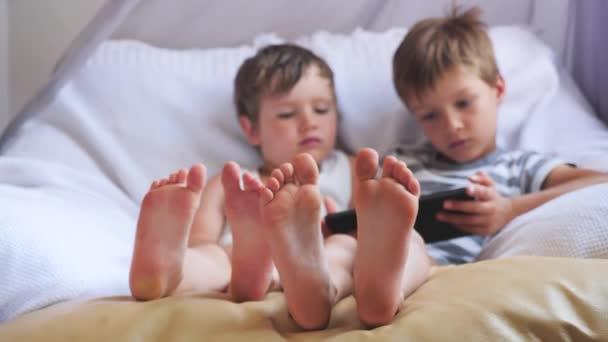 Δύο χαριτωμένα αγόρια, λαμβάνοντας ένα υπόλοιπο κατά τη διάρκεια της ημέρας. Επικεντρωθεί σε αγόρια πόδια. — Αρχείο Βίντεο