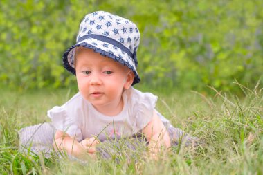 Kız bebek şapkalı, panama. Çimlere yatan toddler.