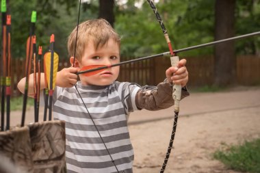 Boy with a bow and arrow. Children and sports. clipart