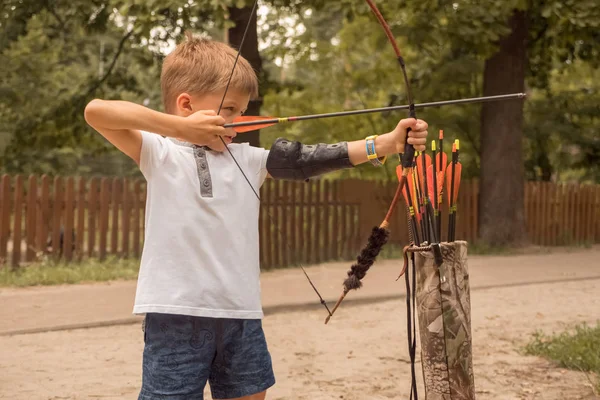 Boy with a bow and arrow. Children and sports. — Stock Photo, Image